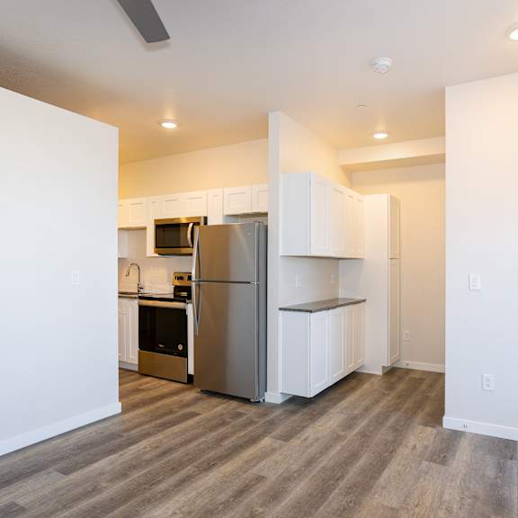 Thumbnail 5 of 7 Kitchen with white cabinets, refrigerator and stove top oven at Brownstones at Palisade Park, Broomfield.