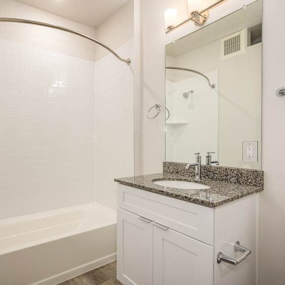 Thumbnail 7 of 7 A white bathroom with a tub, sink, mirror and shower at Brownstones at Palisade Park, Broomfield,  Colorado.