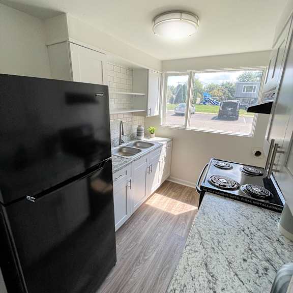 Thumbnail 5 of 8 A black fridge in a kitchen with a black stove top.