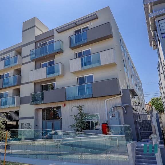 a white apartment building with balconies and a glass staircase