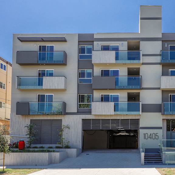a white apartment building with blue balconies and a garage