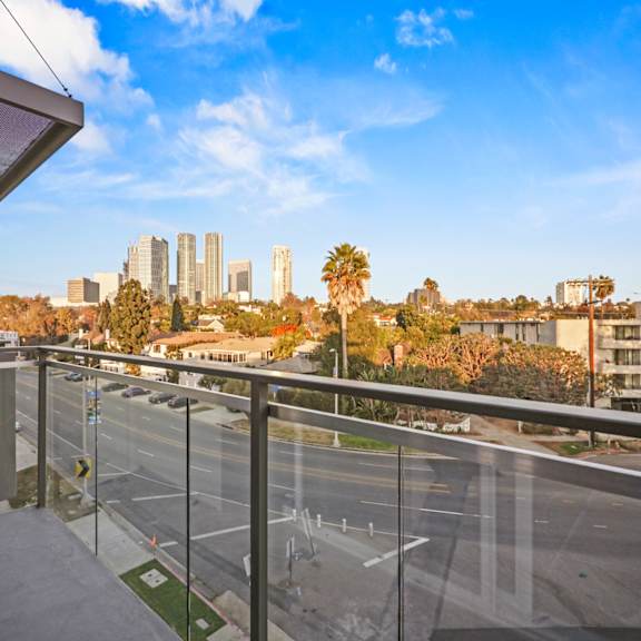 a view from a balcony overlooking a city street with buildings in the distance.
