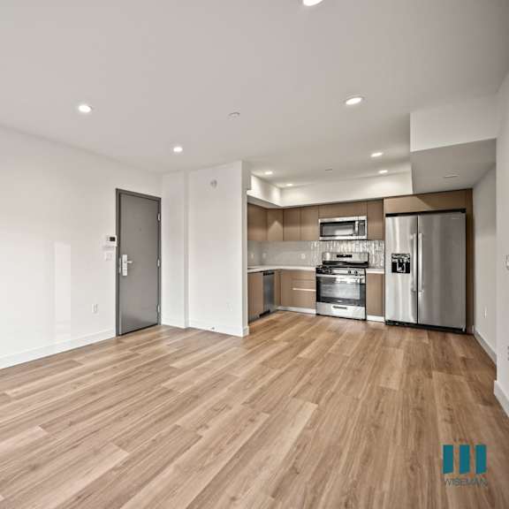 a kitchen with a white wall and wooden floors.