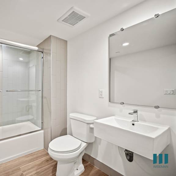 a white bathroom with a toilet, sink, and a glass shower stall.