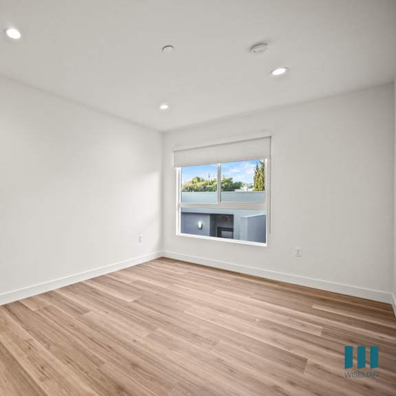 a room with a white door and a window showing a view of a building and trees.