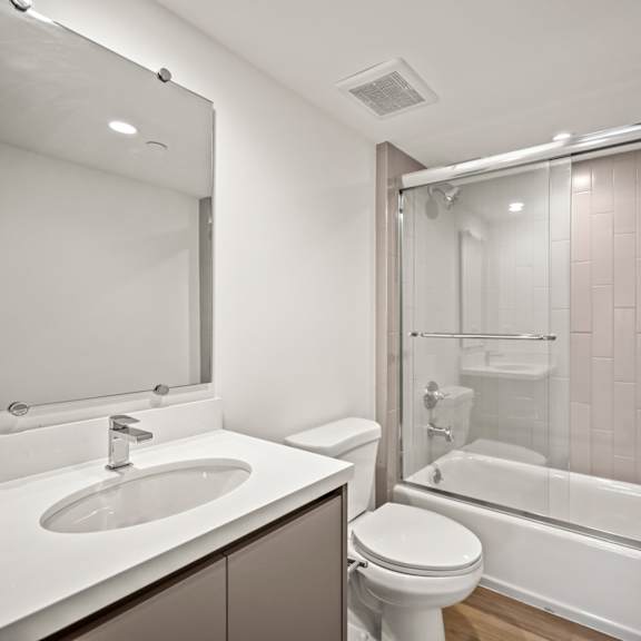 a modern bathroom with a white sink, toilet, and bathtub.
