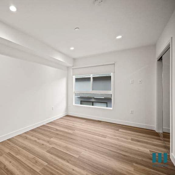 a spacious room with wooden flooring and a window.