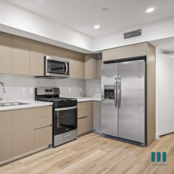 a modern kitchen with stainless steel appliances and wooden floors.