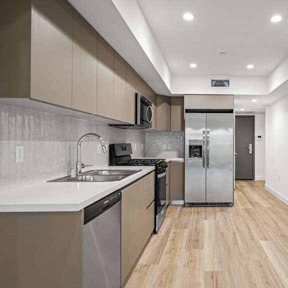 a modern kitchen with wooden floors and stainless steel appliances.