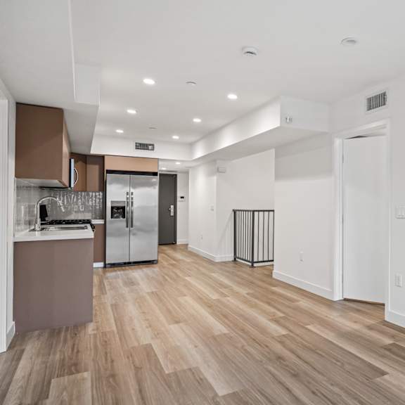a kitchen area with a refrigerator, sink, and cabinets.