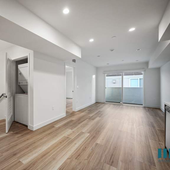 a spacious room with wooden floors and a staircase with a metal railing.