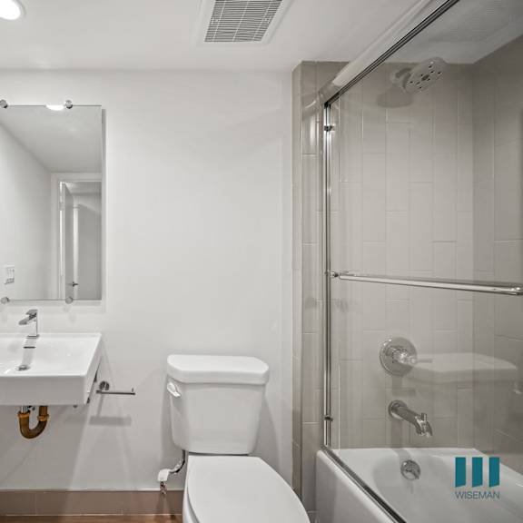 a white bathroom with a sink, toilet, and shower.