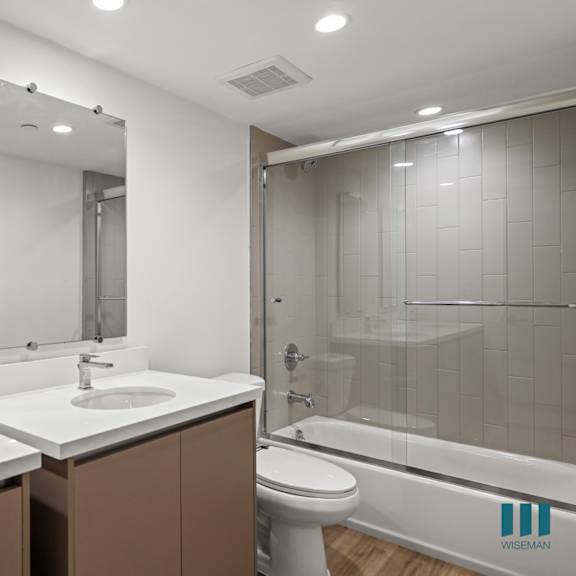a bathroom with a white sink and brown cabinetry.