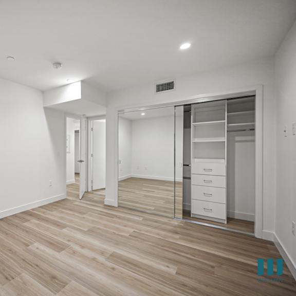 a spacious room with wooden flooring and white walls.