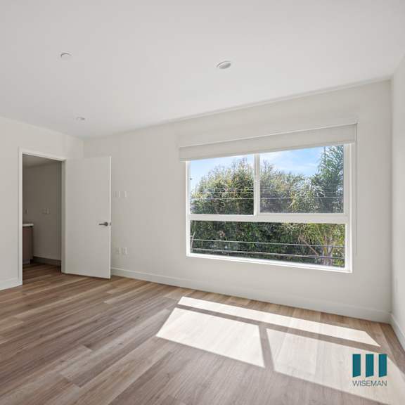 a living room with white walls and wooden floors and a window