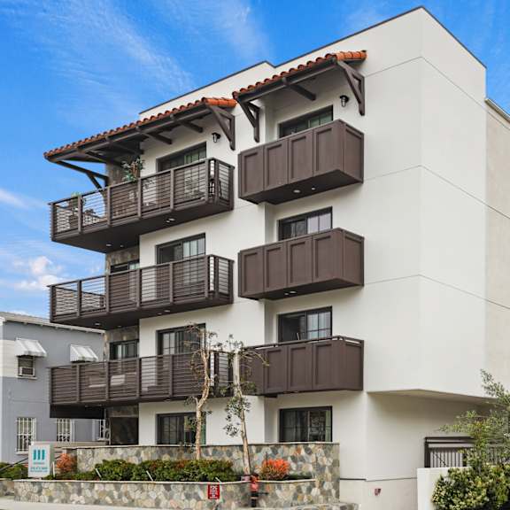 a white apartment building with brown balconies