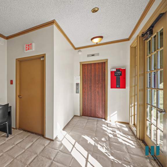 a conference room with a table and chairs and an exit sign on the wall.