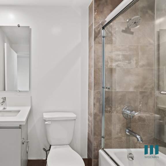 bathroom with shower bath with glass door and vanity cabinet storage