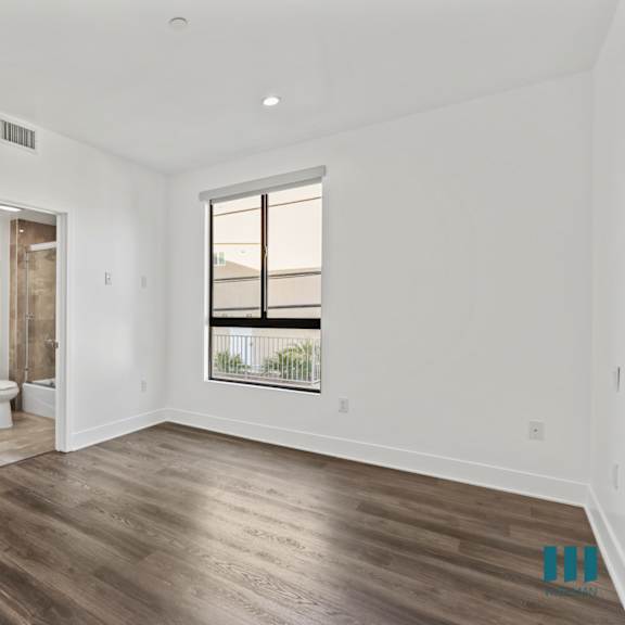 bedroom with bathroom, vinyl flooring, and windows