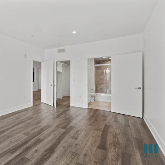 bedroom with bathroom, walk-in closet, and vinyl flooring