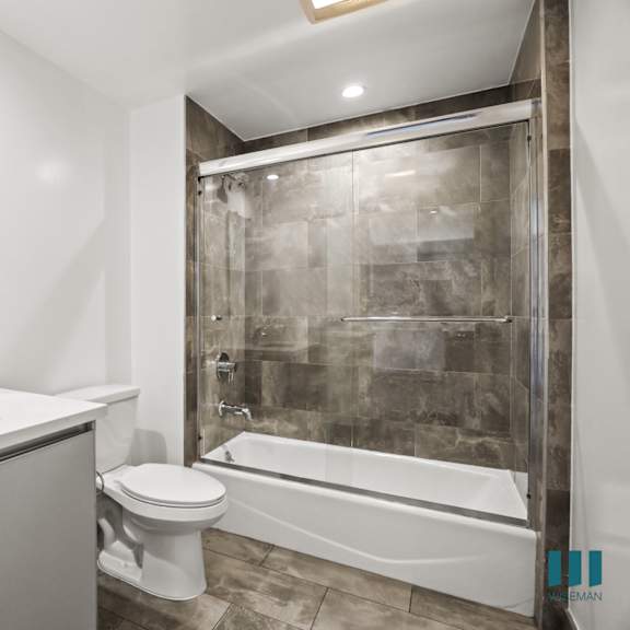 bathroom with shower bath with glass door, and vanity cabinet storage