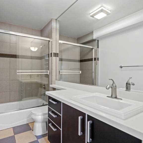 bathroom with bathtub with glass doors and cabinet storage
