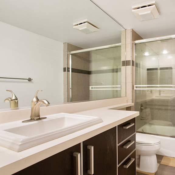 bathroom with bathtub with glass doors and cabinet storage