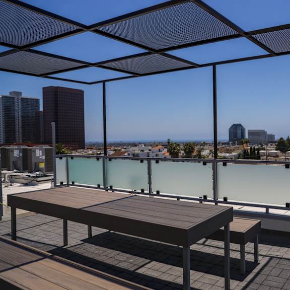 a view of the city from a rooftop terrace with a table and benches