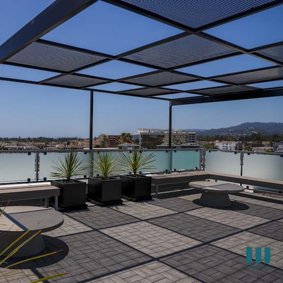 a roof terrace with tables and chairs overlooking a body of water