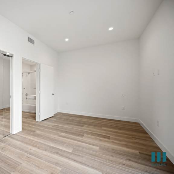 a living room with white walls and wood floors and a mirrored closet