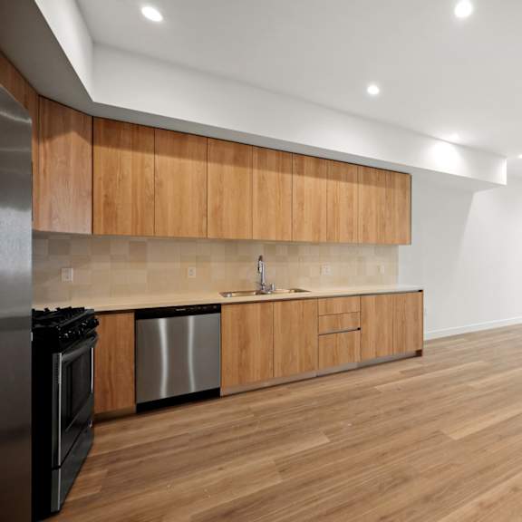 a kitchen and living room with wood floors and wooden cabinets