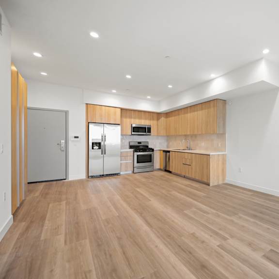 a living room and kitchen with wood floors and white walls