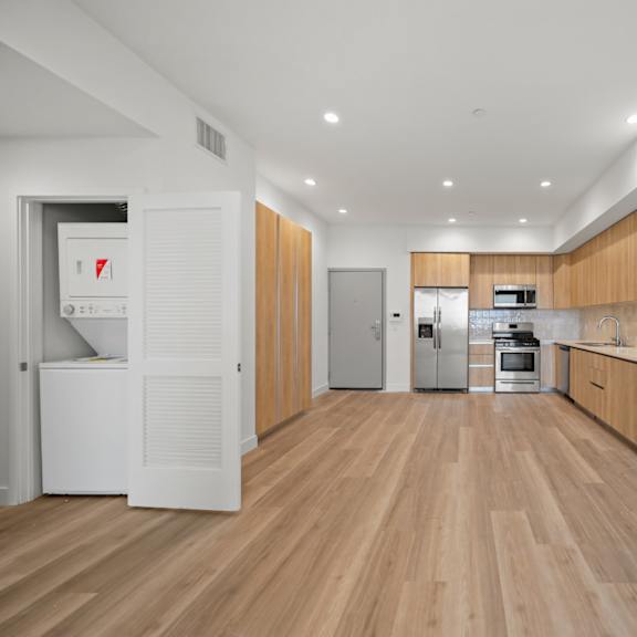 a kitchen with wooden floors and white walls and wooden cabinets