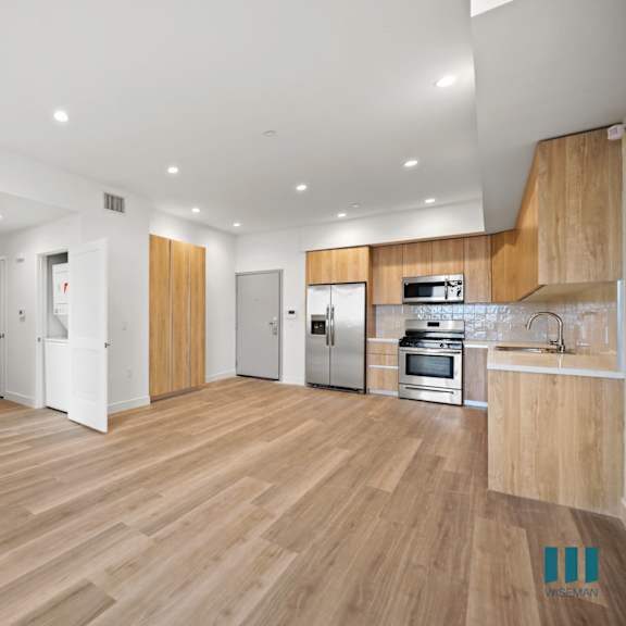 a renovated living room and kitchen with wood floors and white walls