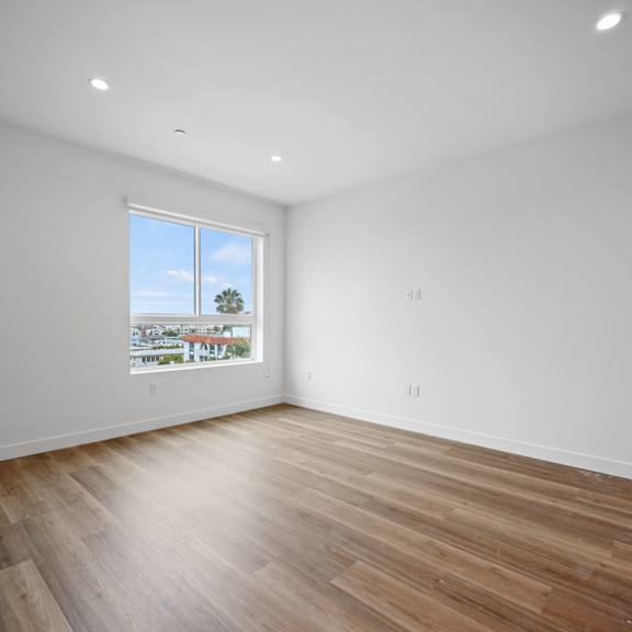 a living room with white walls and wooden floors and a window