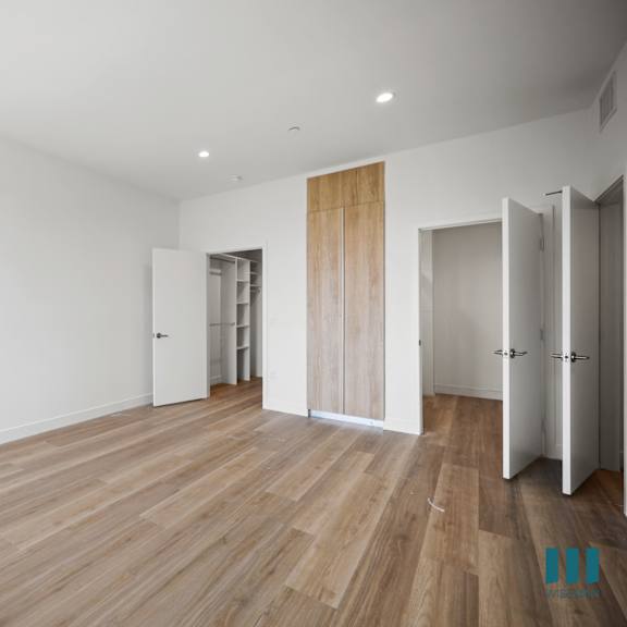 a view of a room with white walls and brown flooring