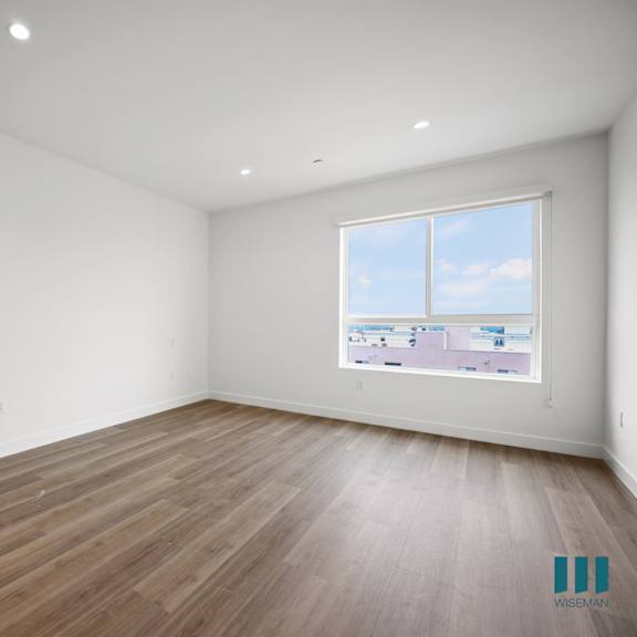 a living room with white walls and wooden floors and a window