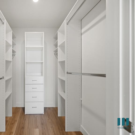 a walk in closet with white walls and white shelves and drawers