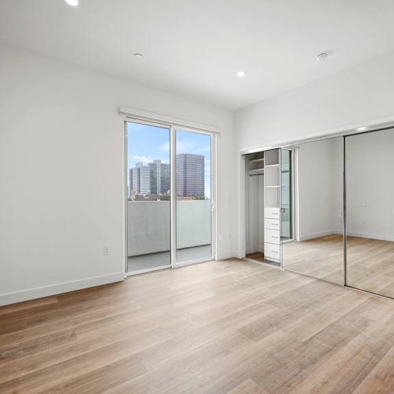 a living room with a hardwood floor and white walls and sliding glass doors