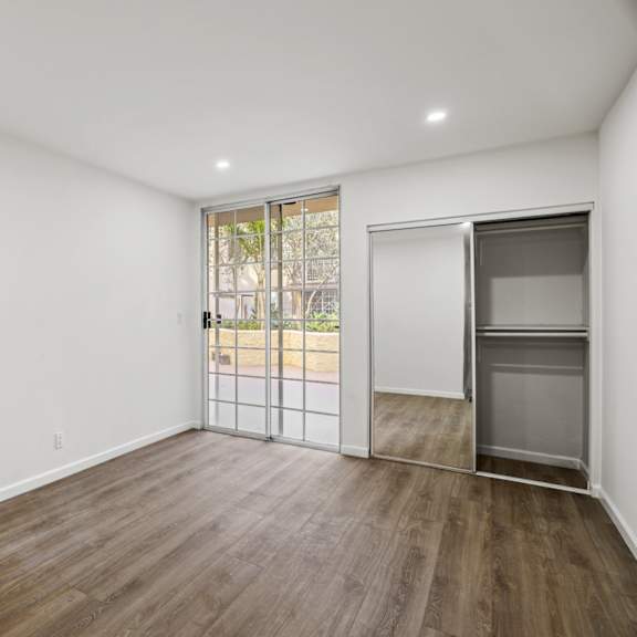 bedroom with mirrored closet with built-in shelving and patio