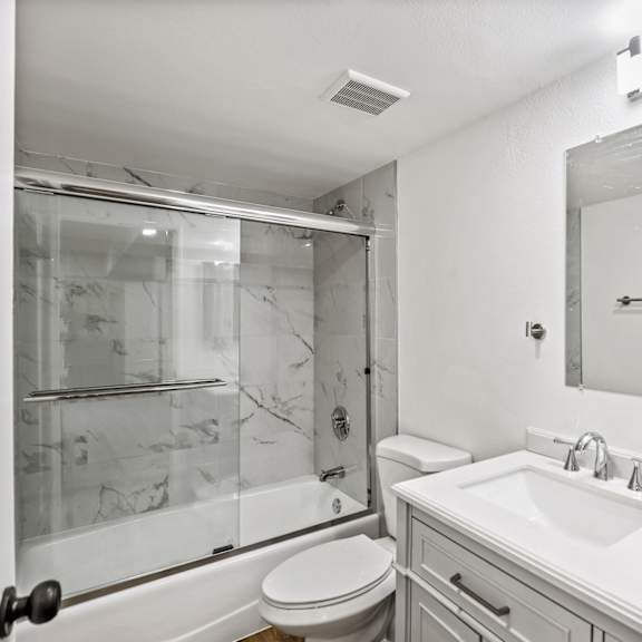 bathroom with bathtub with glass doors