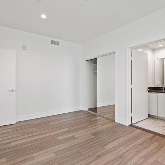 bedroom with bathroom, mirrored closet, recessed lighting, and vinyl flooring