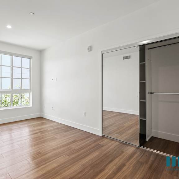 bedroom with mirrored closet, vinyl flooring, and large windows