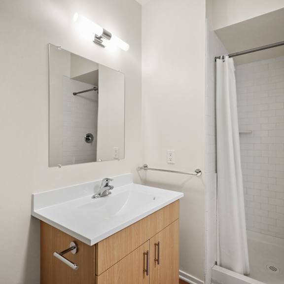 a bathroom with a sink and a shower and a mirror
