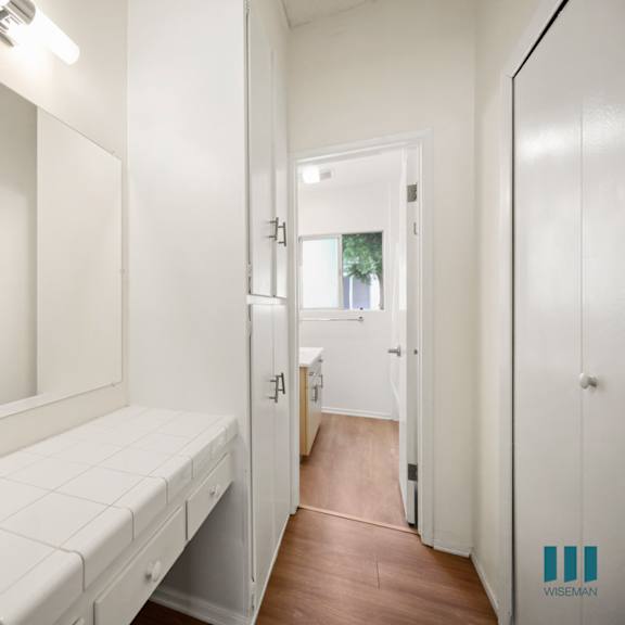 a white bathroom with a mirror and a white bench