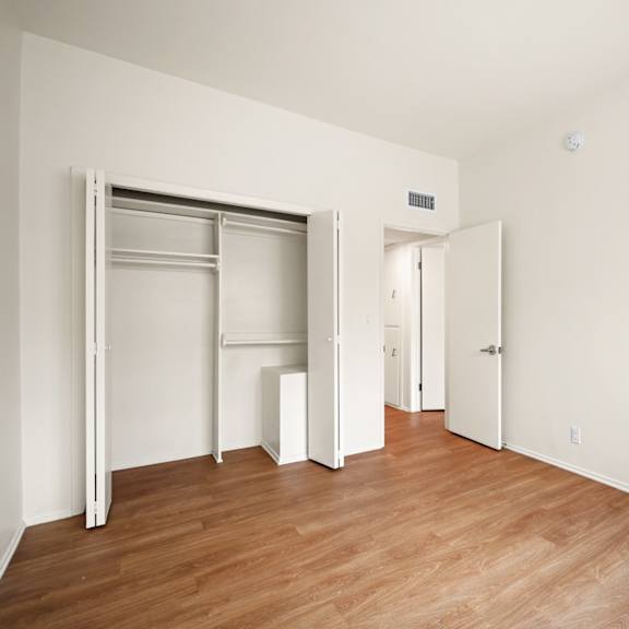 a bedroom with a wood floor and white walls and sliding closet doors