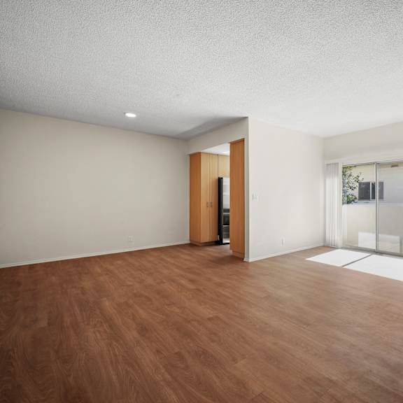 an empty living room with wood flooring and white walls