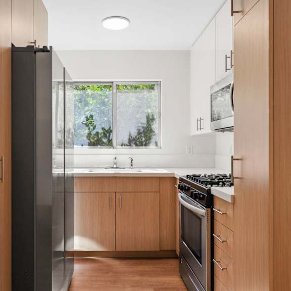 a kitchen with wooden cabinets and a stove and a window