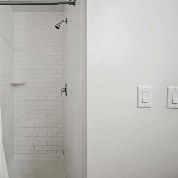 a white bathroom with a shower and a white shower curtain