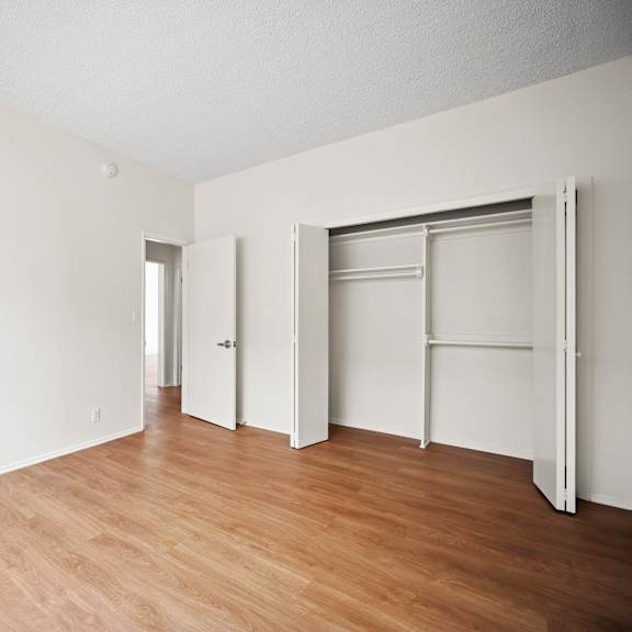 an empty room with wood floor and white walls and sliding closet doors